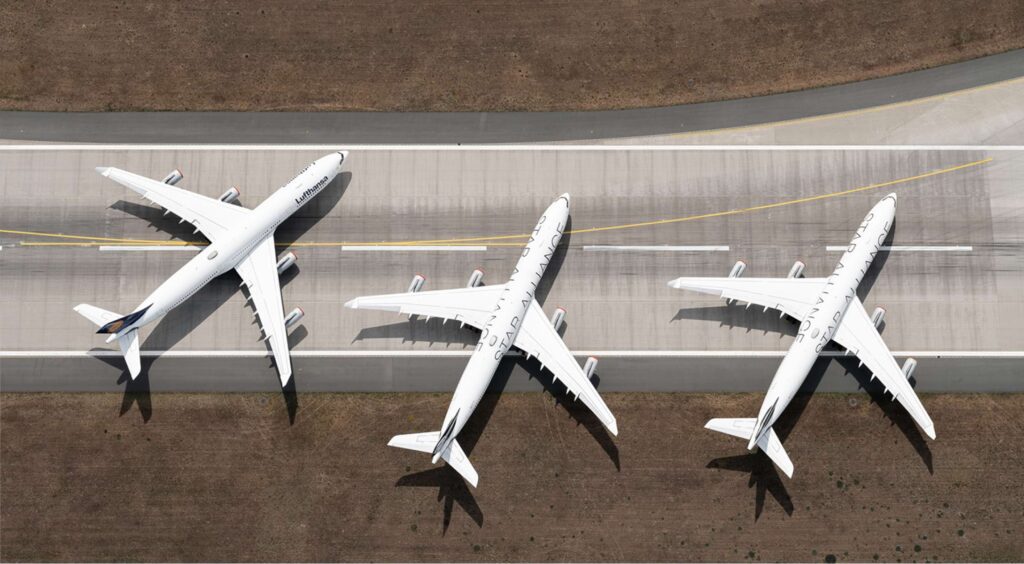 a group of three airplanes sitting on top of an airport runway.
