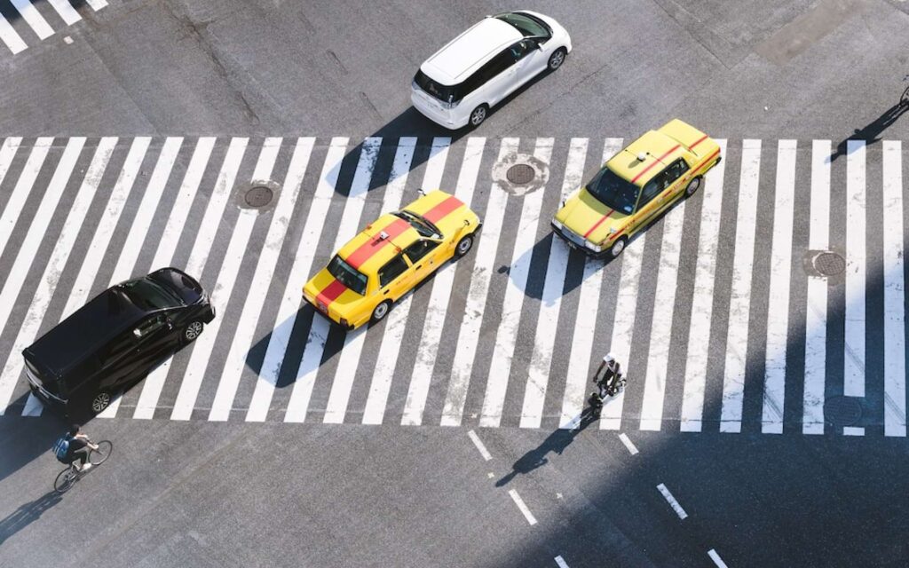 a group of cars driving down a street next to a crosswalk.