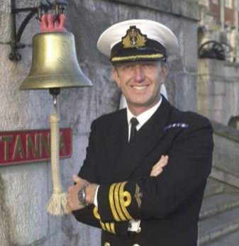a man in a navy uniform standing next to a bell.