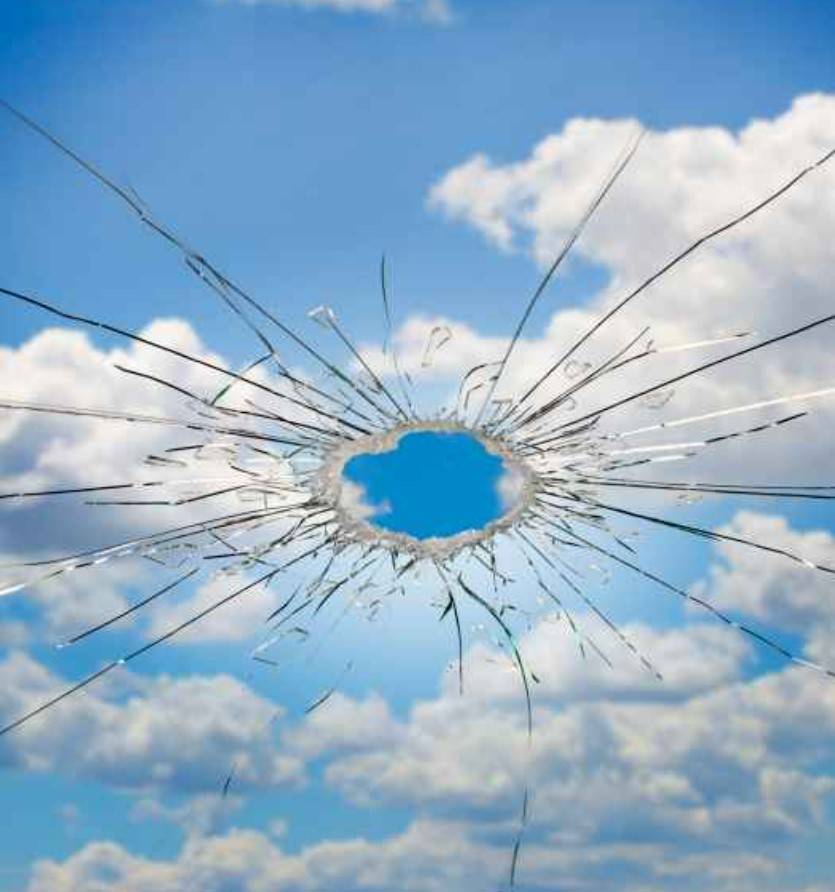 a broken glass window with a blue sky in the background.
